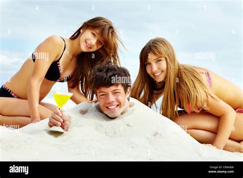 Zwei Mädchen im Bikini und glücklicher Kerl mit Cocktail Spaß am Sandstrand Stockfotografie Alamy