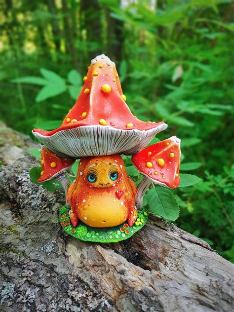 A Small Toy Mushroom Sitting On Top Of A Tree Branch In The Woods With