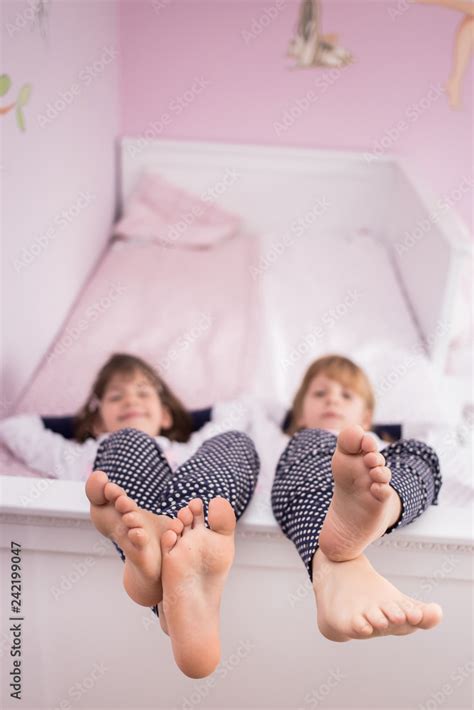 Two Cute Girls Lying On Their Bed Showing Their Feet Foto De Stock