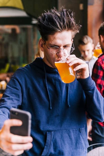 Hombre Joven Que Bebe El Vidrio De Cerveza Que Toma El Selfie En