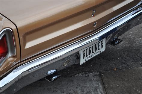 an old brown car parked on the side of the road with its license plate ...