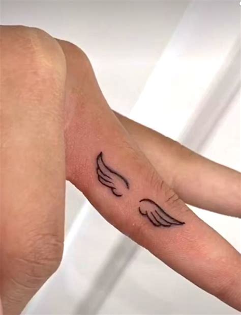 A Small Wing Tattoo On The Left Inner Arm And Wrist Is Shown In Black Ink