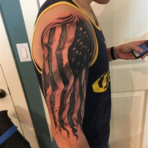 A Man With An American Flag Tattoo On His Arm Is Looking At His Cell Phone
