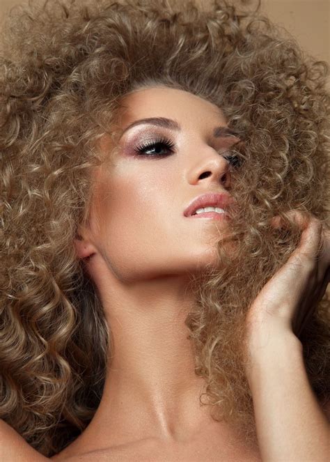 A Beautiful Woman With Curly Hair Posing For The Camera