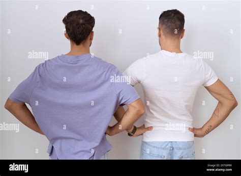 Homosexual Gay Couple Standing Over White Background Standing Backwards Looking Away With Arms