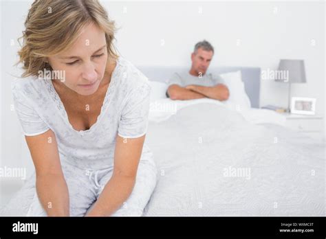 Couple Sitting On Opposite Ends Of Bed After A Fight At Home In Bedroom