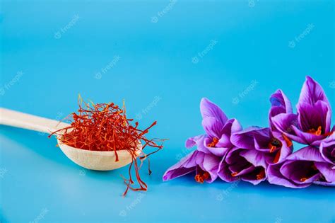 Premium Photo Saffron Stamens In A Wooden Spoon Crocuses On A Blue