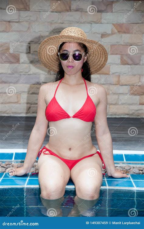 Pretty Asian Woman Wearing Red Bikini Sitting At Swimming Pool Edge