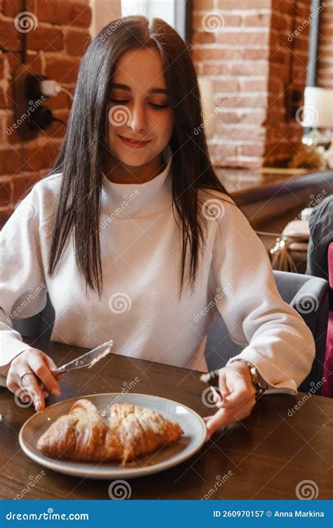 The Brunette Is Working With A Tablet At A Table In A Cafe Drinks Latte Coffee And Eats A