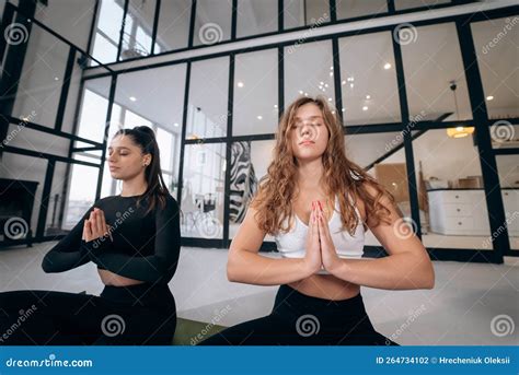 Two Young Women Meditating In Lotus Pose With Hands In Namaste Stock