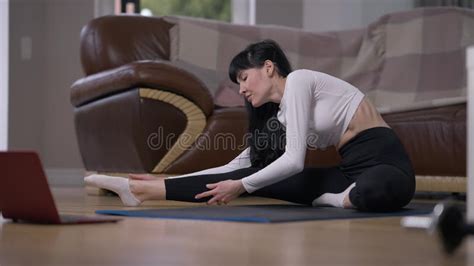 Attractive Slim Fit Sportswoman Warming Up Muscles Stretching Legs