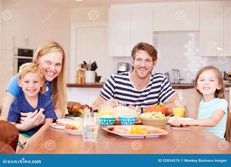 Familia Que Disfruta De La Comida En Casa Junto Foto De Archivo