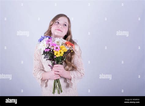 Smiling Twelve Year Old Girl With Long Dirty Blonde Hair Holding Colorful Bouquet Of Daisies