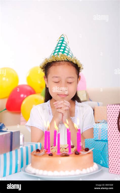 Girl making wish in front of birthday cake Stock Photo - Alamy
