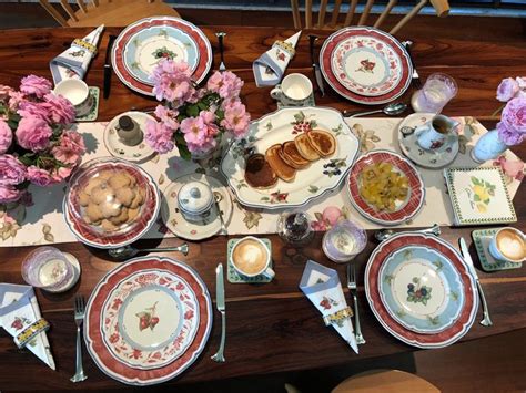 The Table Is Set With Plates Silverware And Pink Flowers On Its