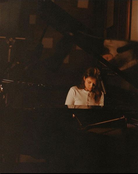 A Woman Sitting In Front Of A Black Piano