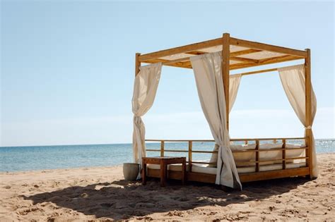 Una Cama En La Playa Con Un Dosel Encima Foto Premium