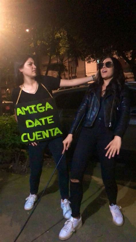 Two Women Standing Next To Each Other On The Sidewalk With One Holding