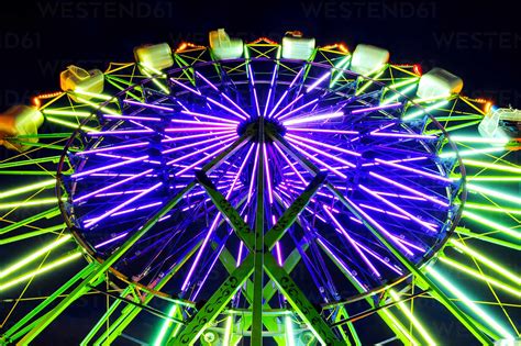 Neon Ferris Wheel Ride At Amusement Park At Night Stock Photo