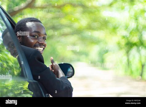 African business man driving and smiling while sitting in a car with ...