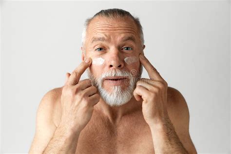 Portrait Of Handsome Mature Gray Haired Bearded Man Applying Face