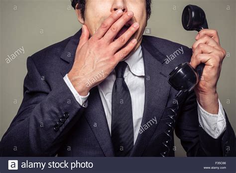 A Young Businessman Is On The Phone And Covering His Mouth In Shock