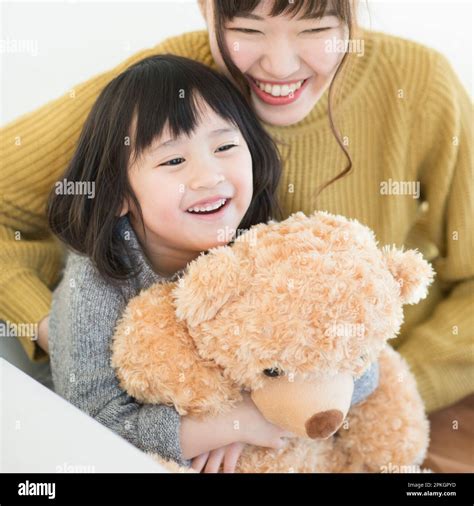 Mother Cuddling With Smiling Girl Holding Stuffed Bear Stock Photo Alamy