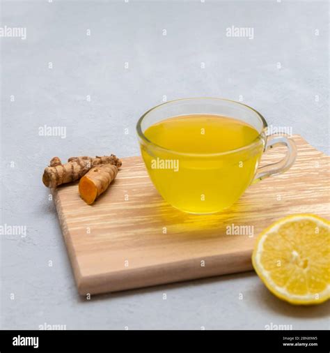 Lemon Ginger Turmeric Tea In A Glass Cup On Neutral Grey Background