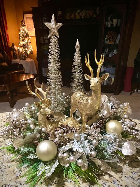 A Christmas Centerpiece With Gold Deer Pine Cones And Silver Baubles