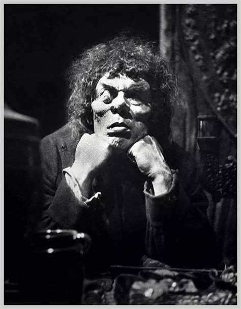 An Old Black And White Photo Of A Man Sitting At A Table With His Hand