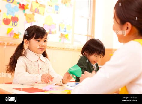 Nursery Teacher Teaching Origami To Children Stock Photo Alamy