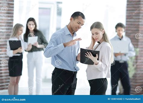 Employees Discussing Business Document Standing In The Office Stock