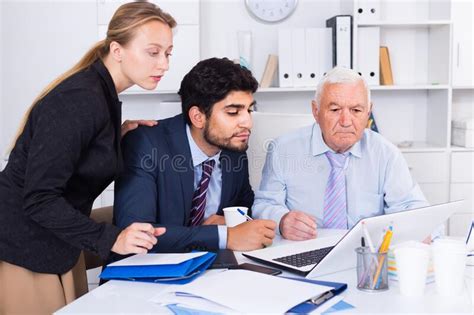 Office Workers Are Demonstrating Reports On Laptop To Mature Boss Stock