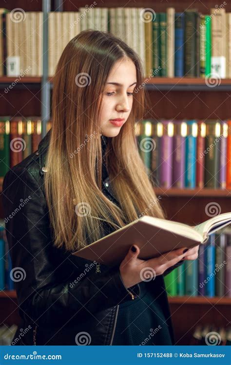 Hermosa Adolescente Leyendo Un Libro En La Biblioteca Foto De Archivo