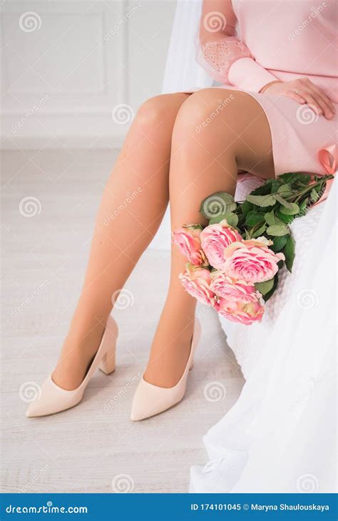 Female Beautiful Long Legs Next To Rose Flowers Elegant Nude Beige Shoes For The Bride Stock