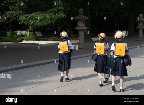 Three Japanese middle school girls wearing sailor uniforms and cute hats walking on their way ...