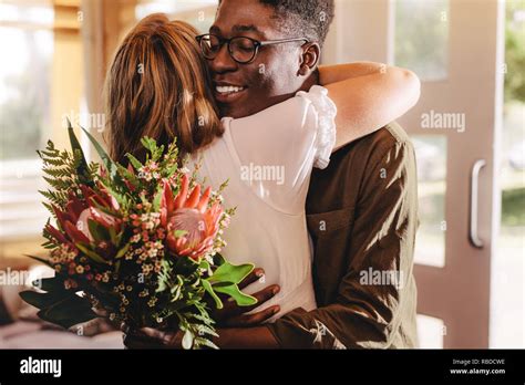 Young african man hugging his girlfriend standing in cafe. Young guy ...