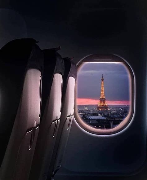 An Airplane Window With The View Of The Eiffel Tower At Dusk From Inside