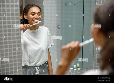 Beautiful Woman Brushing Teeth In Front Of Her Bathroom Mirror Morning