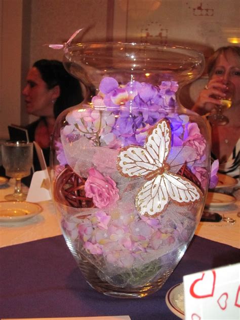 A Vase Filled With Lots Of Flowers On Top Of A Table Next To Two Women