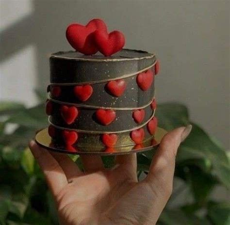 A Hand Holding A Cake With Red Hearts On It S Top And The Bottom