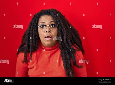 Plus Size Hispanic Woman Standing Over Red Background Afraid And Shocked With Surprise And