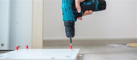 Premium Photo Man Using A Cordless Screwdriver Assembling Furniture