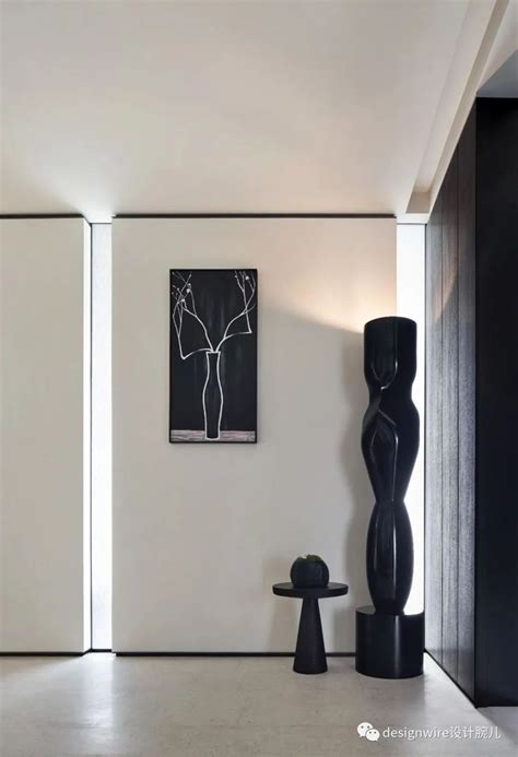 A Black And White Room With Art On The Wall Two Vases And A Table