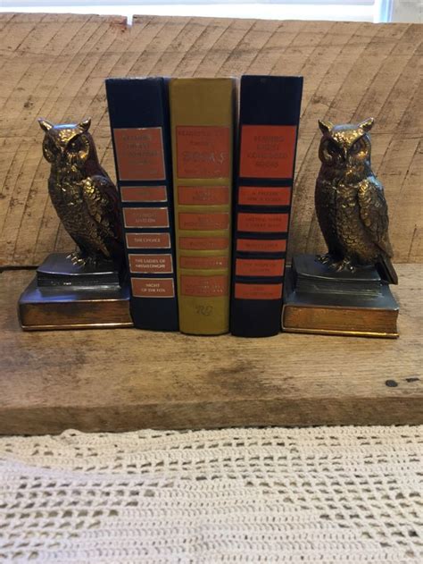 Two Bookends With An Owl Statue Sitting On Top Of Them Next To Each Other