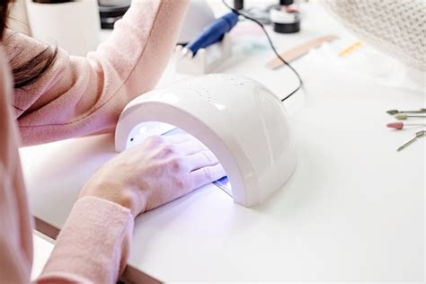 Premium Photo Woman In Manicure Salon Drying Her Nails In A Uv Lamp