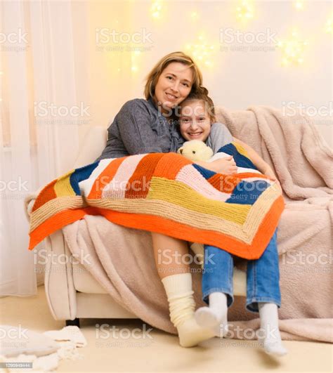 Portrait Of A Mother And Daughter Sitting On A Sofa At Home Two People