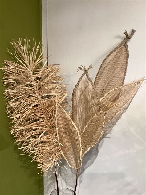 Two Dried Plants In A Glass Vase On A Table