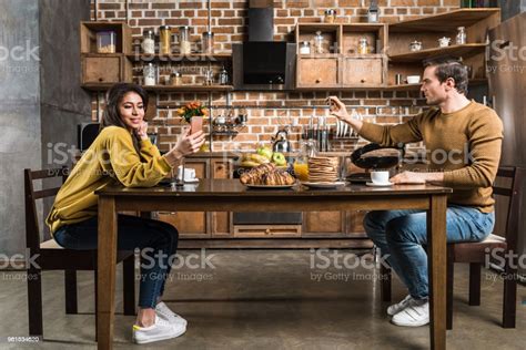 아침 식사 하는 동안 스마트폰 사용 하는 다민족 부부의 모습 가정 생활에 대한 스톡 사진 및 기타 이미지 가정 생활 과일