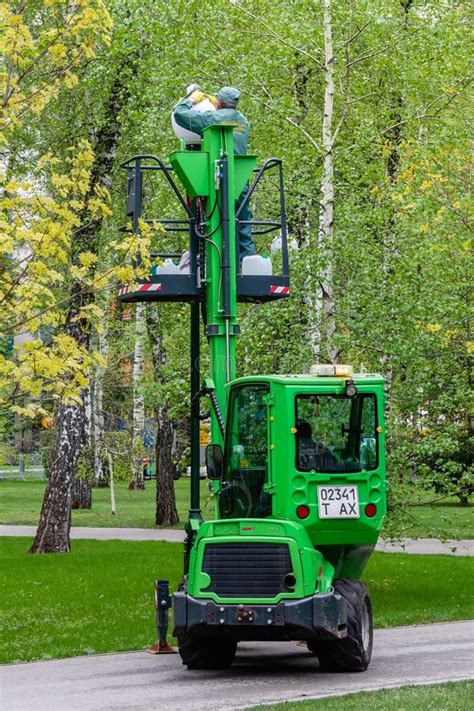 A Utility Worker Cleans a Street Lamp on a Green Aerial Platform in a ...